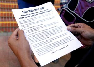 In this Monday, Oct. 19, 2015 photo, Jerome Palma holds a flyer given to him by Alexander Rowson outside Everett Middle School in San Francisco. A student election at a mostly black and Hispanic middle school turned into a fierce debate about the democratic process when the school's principal delayed announcing the election results over concerns they did not reflect the school's diverse student body. (Connor Radnovich/San Francisco Chronicle via AP) MANDATORY CREDIT FOR PHOTOGRAPHER AND SF CHRONICLE; NO SALES; MAGS OUT; TV OUT