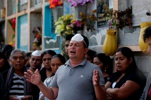 A man prays during the burial of five mudslide victims at the Santa Catarina Pinula cemetery on the outskirts of Guatemala City, Tuesday, Oct. 6, 2015. Prosecutors in Guatemala said Tuesday they have opened an investigation into who allowed homes to be built in an unsafe area of Cambray where a massive mudslide killed more than 100 people. (AP Photo/Moises Castillo)