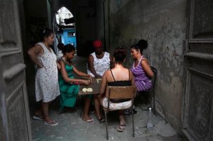 FILE - In this Sept. 16, 2015, file photo, women play dominoes in a building courtyard in Old Havana, Cuba. The sprouting of high-end clubs and bars around Havana is unsettling to many in Cuba who grew up believing in equality as a tenet of the revolution, and now see foreigners and wealthy Cubans spending many times in one night the roughly $30 monthly salary of the average Cuban state worker. (AP Photo/Ramon Espinosa,File)