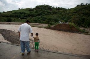 People stand at the edge of a collapsed bridge, overlooking the Ameca River in Cofradia, some 200 km northwest of Guadalajara, Mexico, Saturday, Oct. 24, 2015. Hurricane Patricia made landfall Friday on a sparsely populated stretch of Mexico's Pacific coast as a Category 5 storm, avoiding direct hits on the resort city of Puerto Vallarta and major port city of Manzanillo as it weakened to tropical storm force while dumping torrential rains that authorities warned could cause deadly floods and mudslides. (AP Photo/Eduardo Verdugo)
