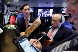 Specialist John McNierney, left, holds a loaf of French bread as he works with traders on the floor of the New York Stock Exchange, during the IPO of Performance Food Group, Thursday, Oct. 1, 2015. (AP Photo/Richard Drew)