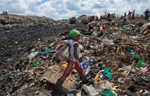 In this photo taken Thursday, Nov. 12, 2015, Joyce Njeri, 8, walks with a torn sack carrying the plastic bottles she has scavenged, at the garbage dump in the Dandora slum of Nairobi, Kenya. Men, women and children traipse through the murky sludge that weaves through mountains of garbage in Nairobi's notorious Dandora dump, hunting for anything that can be recycled to earn themselves enough for their daily bread - some of the poorest of Kenya's poor and those likely to be on Pope Francis' mind when he makes his first trip to Africa this week and brings his message of environmental stewardship and care for society's most marginal. (AP Photo/Ben Curtis)
