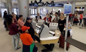 FILE - In this Nov. 25, 2015 file photo, travelers check in their luggage as they prepare to travel at Miami International Airport in Miami. A stronger economy and lower gas prices means Thanksgiving travelers can expect more highway congestions in 2015. Airlines for America, the lobbying group for several major airlines, forecasts 25.3 million passengers will fly on U.S. airlines, up 3 percent from last year.(AP Photo/Alan Diaz)