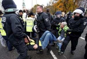 Police officers carry away people who tried  to stop a protest rally of the German party 'Alternative fuer Deutschland, AfD' (Alternative for Germany) in Berlin, Germany, Saturday, Nov. 7, 2015. The  anti-immigration party AfD  has staged a march in Berlin against the German governments migrant policies, with demonstrators chanting Merkel must go and counter-protesters shouting Nazis out.  (AP Photo/Michael Sohn)