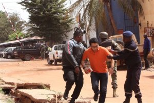 Mali trooper assist a hostage, centre, to leave the scene, from the Radisson Blu hotel to safety after gunmen attacked the hotel in Bamako, Mali, Friday, Nov. 20, 2015. Islamic extremists armed with guns and throwing grenades stormed the Radisson Blu hotel in Mali's capital Friday morning, killing at least three people and initially taking numerous hostages, authorities said.  (AP Photo/Harouna Traore)
