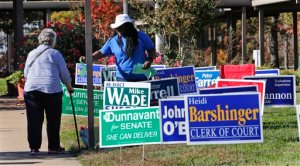 Election volunteer Wenwu Mulbah, of Richmond, center, hands out Republican sample ballots at a polling place in Richmond, Va., Tuesday, Nov. 3, 2015. Democrats look to regain control of the state Senate in today's with both parties spending huge amounts of cash in two key districts, one in Richmond and one in Northern Virginia. (AP Photo/Steve Helber)