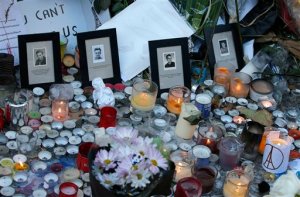 Pictures of victims are placed behind candles  outside the Bataclan concert hall in Paris, Sunday, Nov. 15, 2015. Thousands of French troops deployed around Paris on Sunday and tourist sites stood shuttered in one of the most visited cities on Earth while investigators questioned the relatives of a suspected suicide bomber involved in the country's deadliest violence since World War II.(AP Photo/Christoph Ena)