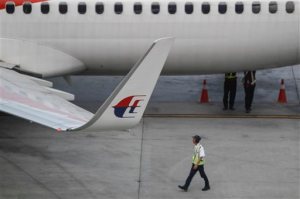 A Malaysia Airlines ground staff walks past a taxied aircraft on the tarmac of Kuala Lumpur International Airport in Sepang, Malaysia, Tuesday, Oct. 13, 2015. A Russian state-controlled missile-maker said Tuesday its investigation of last year's crash of a Malaysia Airlines plane over rebel eastern Ukraine contradicts conclusions from a Dutch probe. (AP Photo/Joshua Paul)