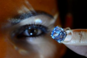 FILE - In this Nov. 4, 2015 file photo a Sotheby's employee displays the rare Blue Moon Diamond during a preview at Sotheby's, in Geneva, Switzerland. The 12.03 carat blue diamond is the largest cushion shaped fancy vivid blue diamond ever appear at auction. It is estimated to sell between 35 and 55 million US dollars. The auction will take place in Geneva, on Nov. 11, 2015. (Martial Trezzini/Keystone via AP, file)