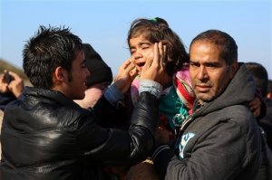 A man tries to calm a girl who arrived with her family on a dinghy from the Turkish coast to the Skala Sikaminias village on the northeastern Greek island of Lesbos on Wednesday, Nov. 11, 2015. More than 770,000 people have arrived in the EU by sea so far this year overwhelming border authorities and receptions centers. (Manolis Lagoutaris/InTime News via AP)  GREECE OUT