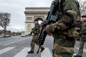 French soldiers cross the Champs Elysees avenue passing the Arc de Triomphe in Paris, Monday, Nov. 16, 2015. While few in the war-weary West want to send ground troops to the areas controlled by Islamic State, it may actually be even harder to find anyone arguing that the aerial bombardment strategy will soon succeed in defeating the radical jihadi group. That is the fundamental contradiction faced by policymakers as they grapple with the meaning of the Paris attacks. (AP Photo/Peter Dejong)