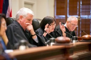FILE- In this Aug. 27, 2015, file photo, Chief Justice Mark Recktenwald, from left, Associate Justice Sabrina S. McKenna, and Associate Justice Michael Wilsonas preside as oral arguments at the Hawaii State Supreme Court. The case involves building one of the world's largest telescopes on Mauna Kea. The Hawaii Supreme Court said Tuesday, Nov. 17, that it is temporarily suspending a permit that allows the giant telescope to be built on a mountain many Native Hawaiians consider sacred. (Craig T. Kojima/Honolulu Star-Advertiser via AP, Pool, File)