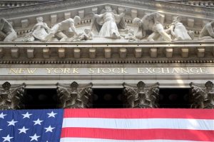 In this July 6, 2015, file photo, an American flag is draped on the exterior of the New York Stock Exchange. International stock markets fell Monday, Nov. 16, 2015, after the attacks in Paris last week sent worries across the world about their possible economic effects. Futures point to Wall Street drifting lower on Monday. (AP Photo/Mark Lennihan, File)