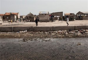 In this photo taken Monday, Oct. 19, 2015, children stand near the sea wall built by the Senegalese government to help stop rising water levels from destroying homes stand on the edge of Rafangue Village, Saloum Delta in Senegal. Faye and thousands of others on these tiny islands and villages in this part of West Africa are living on the frontline of climate change. Not only are water levels here now higher than they used to be, droughts and erratic rain falls lead to floods that carve through the white-shell-lined alleyways, and increased salt levels are poisoning the fresh waters, land and agriculture. (AP Photo/Jane Hahn)