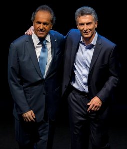 In this Nov. 15, 2015 photo, opposition presidential candidate Mauricio Macri, right, and Daniel Scioli, the ruling party presidential candidate embrace each other on stage at the end of the presidential debate in Buenos Aires, Argentina. Macri will face Scioli in a Nov. 22 runoff. Macri promises to maintain a safety net for the poor but says he will overhaul the economy to address inflation estimated around 30 percent and a byzantine monetary system that has spawned a booming black market. (AP Photo/Natacha Pisarenko)