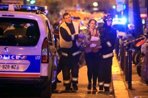 Rescue workers help a woman after a shooting, outside the Bataclan theater in Paris, Friday Nov. 13, 2015.  French President Francois Hollande declared a state of emergency and announced that he was closing the country's borders. (AP Photo/Thibault Camus)