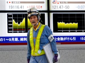 A worker walks past an electronic stock indicator showing the Nikkei 225 was up 1 percent at 19,116.41 in Tokyo Thursday, Nov. 5, 2015.  Chinese stocks surged for a second day Thursday as confidence grew that stimulus measures are helping the world's No. 2 economy to stabilize. Other Asian markets were mixed on renewed expectations that the Federal Reserve's first rate hike in nearly a decade could take place as early as next month.(AP Photo/Shuji Kajiyama)