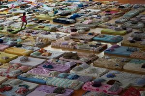 A girl runs between mattresses inside a sports arena where residents are taking refuge after being displaced by bursting dams in Mariana, Minas Gerais state, Brazil, Friday, Nov. 6, 2015. The rupture of two dams at an iron ore mine unleashed a mix of water and mining residue on a village downhill, smothering the enclave of Bento Rodrigues. Only about 10 of the village's around 200 houses were left standing, and cars and other objects were tossed by what survivors described as an eruption of mud. The mine operator Samarco is jointly owned by the Brazilian mining company Vale and Australia's BHP Billiton. (AP Photo/Felipe Dana)