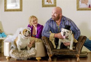 This film still provided by Maza Kong Holdings LLC from the movie "The Dog Wedding" shows, from left, Rosalie Thomass, with Queenie, and Matt Bloom, with Prince, photographed at "Oh My Dog! Boutique & Spa," in Scottsdale, Ariz. In the film, a German businesswoman falls for an American pro wrestler she meets at the dog park, testing her lifelong obedience to her CEO father. (Maza Kong Holdings LLC/via AP)