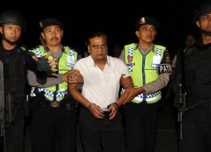 Indian fugitive Rajendra Sadashiv Nikalje, known in India as "Chotta Rajan," center, is escorted by police officers to the Bali airport to be deported, Indonesia, Thursday, Nov. 5, 2015. The alleged organized crime boss, wanted for alleged involvement in several mafia killings and other major crimes in his homeland, was arrested Sunday after arriving at Bali's airport from Sydney based on information from Interpol and Australian authorities. (AP Photo/Firdia Lisnawati)