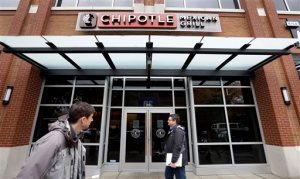 FILE - In this Nov. 9, 2015, file photo, pedestrians walk past a still-closed Chipotle restaurant in Seattle. An outbreak of E. coli that originated in the Pacific Northwest has spread south and east and has now infected people in six states. New cases have been reported in California, New York and Ohio, the Centers for Disease Control and Prevention said Friday, Nov. 20, 2015. (AP Photo/Elaine Thompson, File)