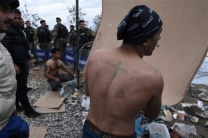 Migrants raise a banner as they demand to be allowed to cross the border to Macedonia, as Macedonian policemen stand guard, near the Greek village of Idomeni, Sunday, Nov. 22, 2015. About 1,300 migrants gathered in the Greek town Idomeni protested Saturday against the decision by Macedonian authorities across the border to turn away migrants who are not from war zones such as Syria, Afghanistan and Iraq. (AP Photo/Giannis Papanikos)