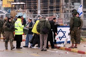 Israeli security stand at the scene of an alleged stabbing attack at Gush Etzion junction in the West Bank on Tuesday, Dec. 1, 2015. A Palestinian attempted to stab a pedestrian at a busy junction outside of Jerusalem when Israeli troops shot and killed him, the military said. (AP Photo/Mahmoud Illean)