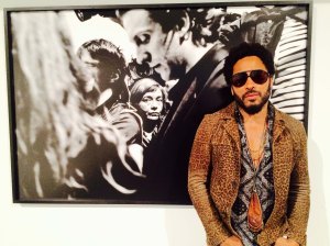 In this image taken from video, Musician Lenny Kravitz stands in front of one of his photos from his exhibit "Flash", which is running in conjunction with Art Basel in Miami Beach, Wednesday, Dec. 2, 2015. Kravitz set out shooting photos on his days off while touring, hoping to capture soulful photographs and people in their environments. (AP Photo/Joshua Replogle)