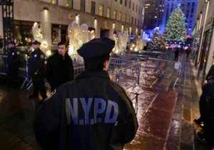 New York Police officers stand watch at an entrance to Rockefeller Center along Fifth Avenue where the Rockefeller Center Christmas tree could be seen after the lighting ceremony, Wednesday, Dec. 2, 2015, in New York. Increased security surrounded the annual event, which drew several thousand spectators. (AP Photo/Julie Jacobson)