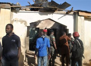 People gather at a damaged building following an attack by Boko Haram in Maiduguri, Nigeria Monday, Dec. 28, 2015. Boko Haram Islamic extremists struck the northeastern Nigerian city of Maiduguri for the first time in months Monday with rocket-propelled grenades and multiple suicide bombers, witnesses said. At least 50 people were killed and the death toll could go higher. (AP Photo/Jossy Ola)