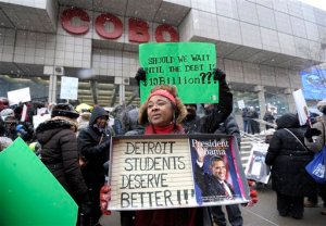 Western International High School teacher Debrah Baskin, 53, of Southfield, and other teachers from Detroit area schools protest outside the Cobo Center, Wednesday, Jan. 20, 2106, only hours before President Barack Obama's visit to the auto show. Faced with another massive sick-out by teachers, the Detroit school district filed a lawsuit Wednesday to try to stop absences that have kept thousands of students at home and left parents scrambling for child care and other quick remedies. The latest sick-out shuttered more than 85 of the struggling district's roughly 100 schools and was timed to coincide with a visit to the city by the Obama. (Todd McInturf/Detroit News via AP) DETROIT FREE PRESS OUT; HUFFINGTON POST OUT; MANDATORY CREDIT