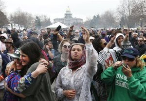 FILE - In this April 19, 2014 file photo, with the Colorado state capitol building visible in the background, partygoers dance to live music and smoke pot during the annual 4/20 marijuana festival in Denver. States that have legalized pot are taking a fresh look at making it easier for out-of-state investors to get in the weed business, saying the pot industrys ongoing difficulty banking means they need new options to finance expansion. (AP Photo/Brennan Linsley, file)