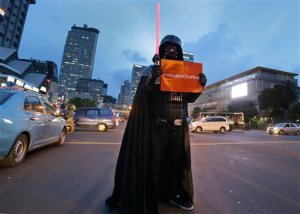 An activist in a Darth Vader costume holds a poster during a rally condemning Thursday's attack, outside the Starbucks cafe where it took place in Jakarta, Indonesia, Friday, Jan. 15, 2016. Indonesians were shaken but refusing to be cowed a day after a deadly attack in a busy district of central Jakarta that has been claimed by the Islamic State group. (AP Photo/Achmad Ibrahim)