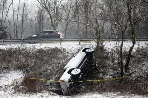 An overturned vehicle lies unattended in the median along Monacan Trail Road south of Charlottesville, Va.,  as snow falls on Friday, Jan. 22, 2016. (Ryan M. Kelly/The Daily Progress via AP) MANDATORY CREDIT