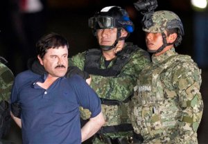 In this Friday, Jan. 8, 2016 photo, Joaquin "El Chapo" Guzman is made to face the press as he's escorted to a helicopter in handcuffs by soldiers and marines at a federal hangar in Mexico City. Guzman's second prison escape in 2015 from a top security prison though a tunnel had embarrassed President Enrique Pena Nieto and made his capture a national priority. (AP Photo/Eduardo Verdugo)
