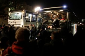 A bus carrying migrants is surround by a crowd of media after the arrival from southern Germany, in front of the chancellery in Berlin, Thursday, Jan. 14, 2016. The bus carrying 31 Syrian refugees was sent from a district councilor in Bavaria, following up on his pledge to Chancellor Angela Merkel that he'd send refugees her way if his district could no longer provide accommodation for them. (AP Photo/Markus Schreiber)