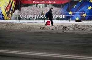 A child walks by a poster that reads "We want our country back" placed outside the government building, where protesters are camping outside for more than one year, in Chisinau, Moldova, Monday, Jan. 25, 2016. More than 15,000 people held an anti-government protest Sunday in the Moldovan capital to demand an early election in the impoverished Eastern European nation, an action that comes after demonstrators stormed Parliament last week as lawmakers approved a new pro-European government.(AP Photo/Vadim Ghirda)