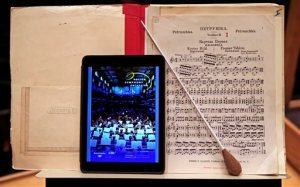 In this Friday, Jan. 15, 2016, photo, an iPad with a Boston Symphony Orchestra interactive program is displayed next to sheet music on a stand at Symphony Hall in Boston. The BSO is loaning iPads to concertgoers during performances in hopes of drawing new audiences to classical music. (AP Photo/Charles Krupa)