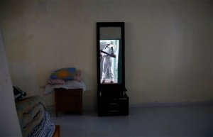 A health worker, reflected in a mirror, sprays insecticide in the home of a woman diagnosed with the Zika virus in Acacias, Colombia, Thursday, Feb. 4, 2016. With more than 20,000 cases confirmed in Colombia and fearing that the virus could affect more than half a million people, the government launched a nationwide prevention campaign. (AP Photo/Fernando Vergara)