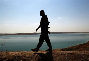 FILE -- In this Aug. 17, 2014 file photo, a Kurdish peshmerga fighter patrols near the Mosul Dam at the town of Chamibarakat outside Mosul, Iraq. An Italian engineering firm is set to ink a contract with the Iraqi government to begin shoring up the countrys rickety Mosul dam. But engineering experts warn the rehabilitation plans are nowhere near a solution and that the key piece of Iraqi infrastructure is beyond repair. (AP Photo/Khalid Mohammed, File)