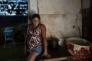 Leydiane da Silva, who's eight months pregnant, rests next to a water storage container, a potential mosquito breeding site, inside her home which stands on stilts above water, trash and sewage, in a slum in Recife, Pernambuco state, Brazil, Monday, Feb. 1, 2016. Zika is spread by the Aedes aegypti mosquito, which is well-adapted to humans, thrives in people's homes and can breed in even a bottle cap's-worth of stagnant water. While anyone can be bitten by Aedes, public health experts agree that the poor are more vulnerable because they often lack amenities that help diminish the risk, such as air conditioning and window screens. (AP Photo/Felipe Dana)