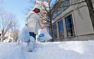 Kumalara Romeo with plastic bags on her shoes carries her belongings along a snow covered road as area residents dig out from a mammoth snowstorm in Richmond, Va., Sunday, Jan. 24, 2016. Despite the break in the weather, the Virginia Department of Transportation is echoing the advice of Gov. Terry McAuliffe: stay off the roads.  (AP Photo/Steve Helber)