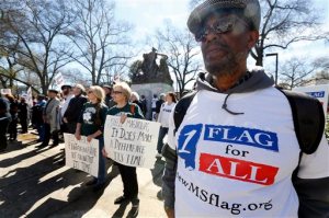 FILE - In this Thursday, Feb. 18, 2016 file photo, Milton Phelps of Jackson, right, stands with Maureen Phillips, center, and her sister Dixie Daniels, both of Gulfport, in calling for a change to the current Mississippi state flag at a rally to remove the Confederate battle emblem from the flag at the state Capitol in Jackson, Miss. Mississippi Gov. Phil Bryant is proclaiming April 2016 as Confederate Heritage Month, but without mentioning slavery. He signed it days before legislators killed bills that would have either removed the Confederate battle emblem from the 122-year-old state flag or stripped state money from colleges and local governments that refuse to fly the current banner. (AP Photo/Rogelio V. Solis, File)
