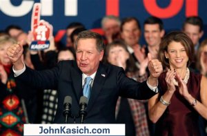 With his wife Karen at his side Republican presidential candidate Gov. John Kasich, R-Ohio, cheers with supporters Tuesday, Feb. 9, 2016, in Concord, N.H. , at his primary night rally. (AP Photo/Jim Cole)