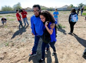 A father and daughter reunite in a vacant field, Friday, Feb. 12, 2016, in Glendale, Ariz., after two students were shot and killed at Independence High School in the Phoenix suburb. The danger at the campus was over, police said, as worried parents crowded stores nearby to meet their children.  (AP Photo/Matt York)
