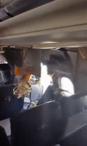 A hole is photographed in a plane operated by Daallo Airlines as it sits on the runway after an emergency landing at the airport in Mogadishu, Somalia Tuesday Feb. 2, 2016. Officials at Somalia's civil aviation authority said Wednesday Feb. 3, 2016 that they had found no evidence so far of a criminal act in an explosion in an airliner which took off from Mogadishu's airport and returned for an emergency landing. (Awale Kullane, via AP)