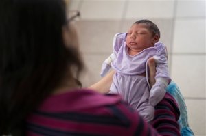 Cassiana Severino holds her daughter Melisa Vitoria, born with microcephaly at the IMIP hospital in Recife, Pernambuco state, Brazil, Wednesday, Feb. 3, 2016. The Zika virus is spread by the Aedes aegypti mosquito, which is well-adapted to humans, thrives in people's homes and can breed in even a bottle cap's-worth of stagnant water. The Zika virus is suspected to cause microcephaly in newborn children. (AP Photo/Felipe Dana)