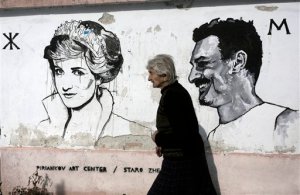 Sabka, 82, passes in front of a mural depicting portrait of Diana Princess of Wales, in the Bulgarian village of Staro Zhelezare on Wednesday, Jan. 27, 2016. The sleepy village of Staro Zhelezare  in central Bulgaria is harnessing the power of celebrities, hoping for an economic revival through art.  Outdoor murals in the village feature local people alongside celebrities on their homes. Homeowners are depicted with personalities such as Pope Francis, Queen Elizabeth II, Angela Merkel, Indira Gandhi, Margaret Thatcher, Barack Obama and Fidel Castro. (AP Photo/Valentina Petrova)