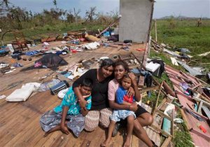 Sanjogeeta Kiran, right, with her sister Sulva Kiran, second left, and her children Shivendera, left, and Raajeen, sit amid the debris of their home in RakiRaki, Fiji, Wednesday, Feb. 24, 2016, after cyclone Winston ripped through the island nation. The cyclone tore through Fiji over the weekend with winds that reached 177 miles (285 kilometers) per hour, making it the strongest storm in Fiji's recorded history. (Brett Phibbs/New Zealand Herald via AP) NEW ZEALAND OUT, AUSTRALIA OUT