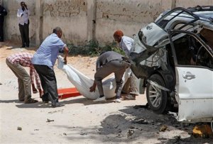 Somali officials remove the body of former Somali defense minister Muhyadin Mohamed Haji, from the scene of a car bomb in Mogadishu, Somalia, Monday, Feb. 15, 2016.  Muhyadin Mohamed Haji worked under Somalis interim government in 2008. (AP Photo/Farah Abdi Warsameh)